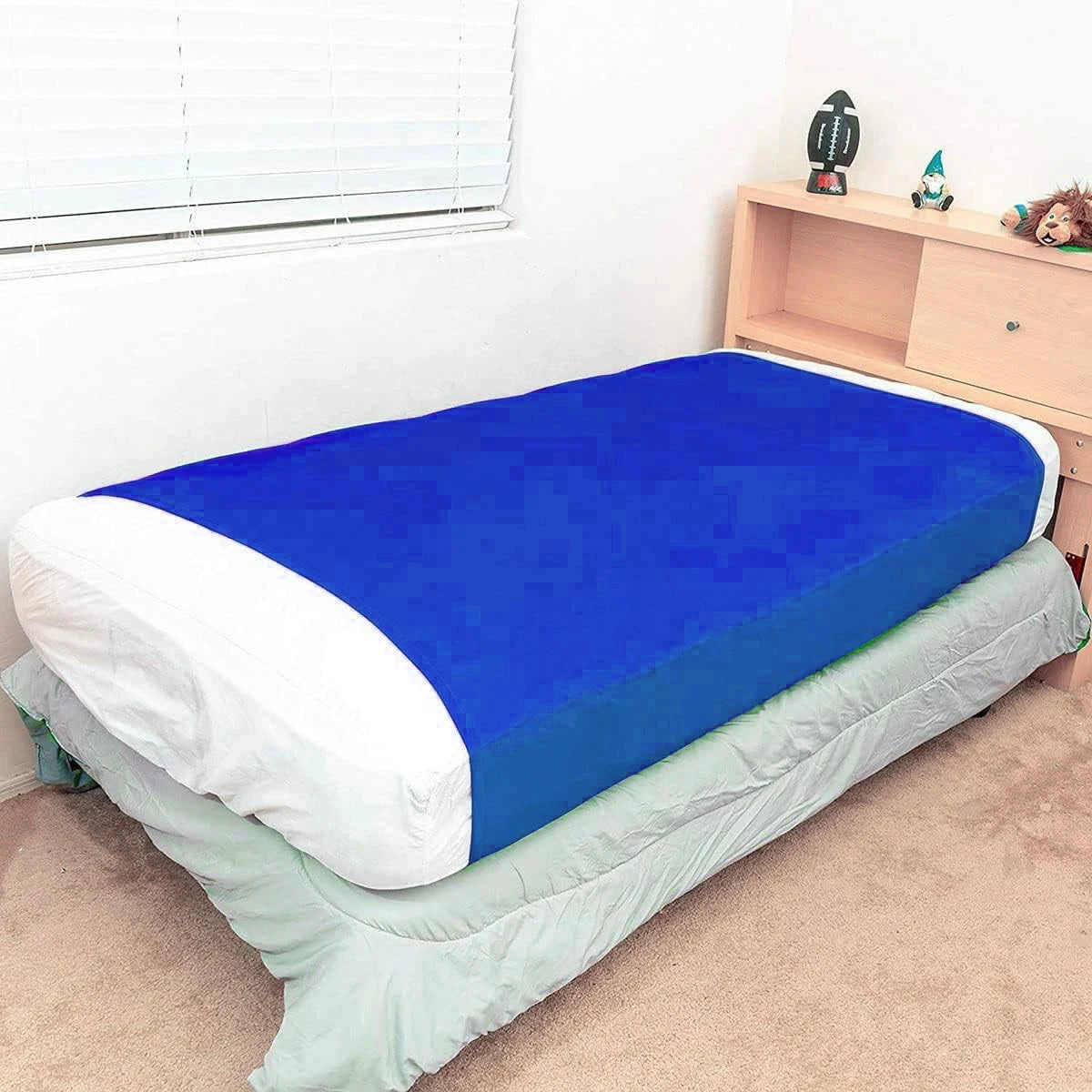 a bed with a fitted blue compression blanket for special needs covering the mattress