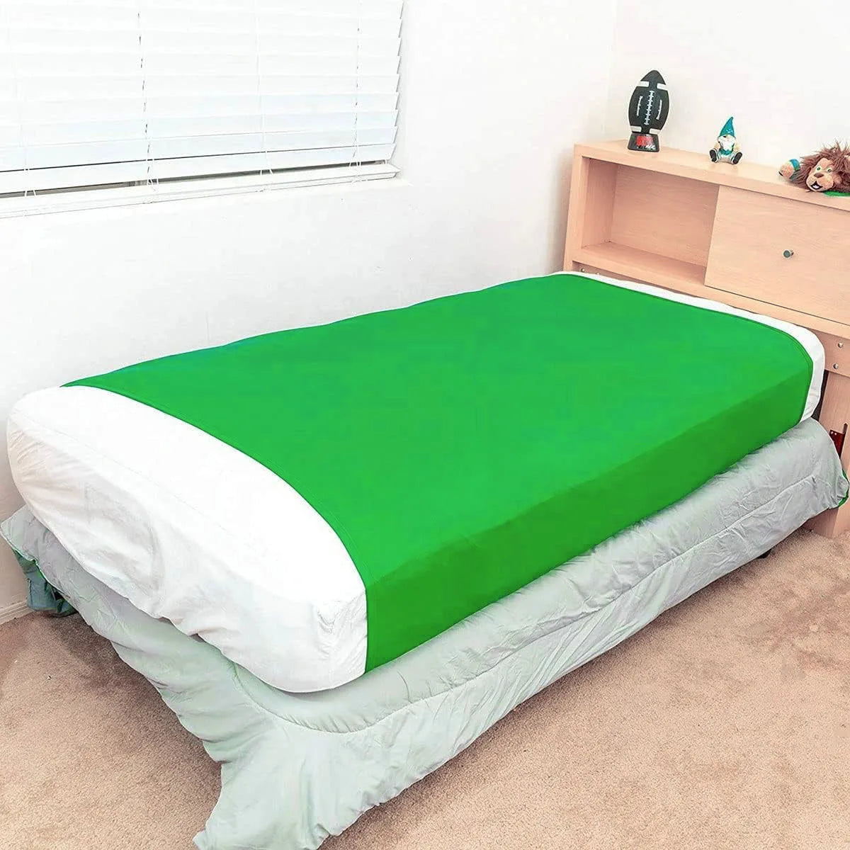 a bed with a fitted green compression blanket for special needs covering the mattress