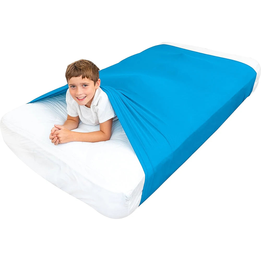 Child lying on a bed with a blue fitted compression blanket for special needs covering the mattress