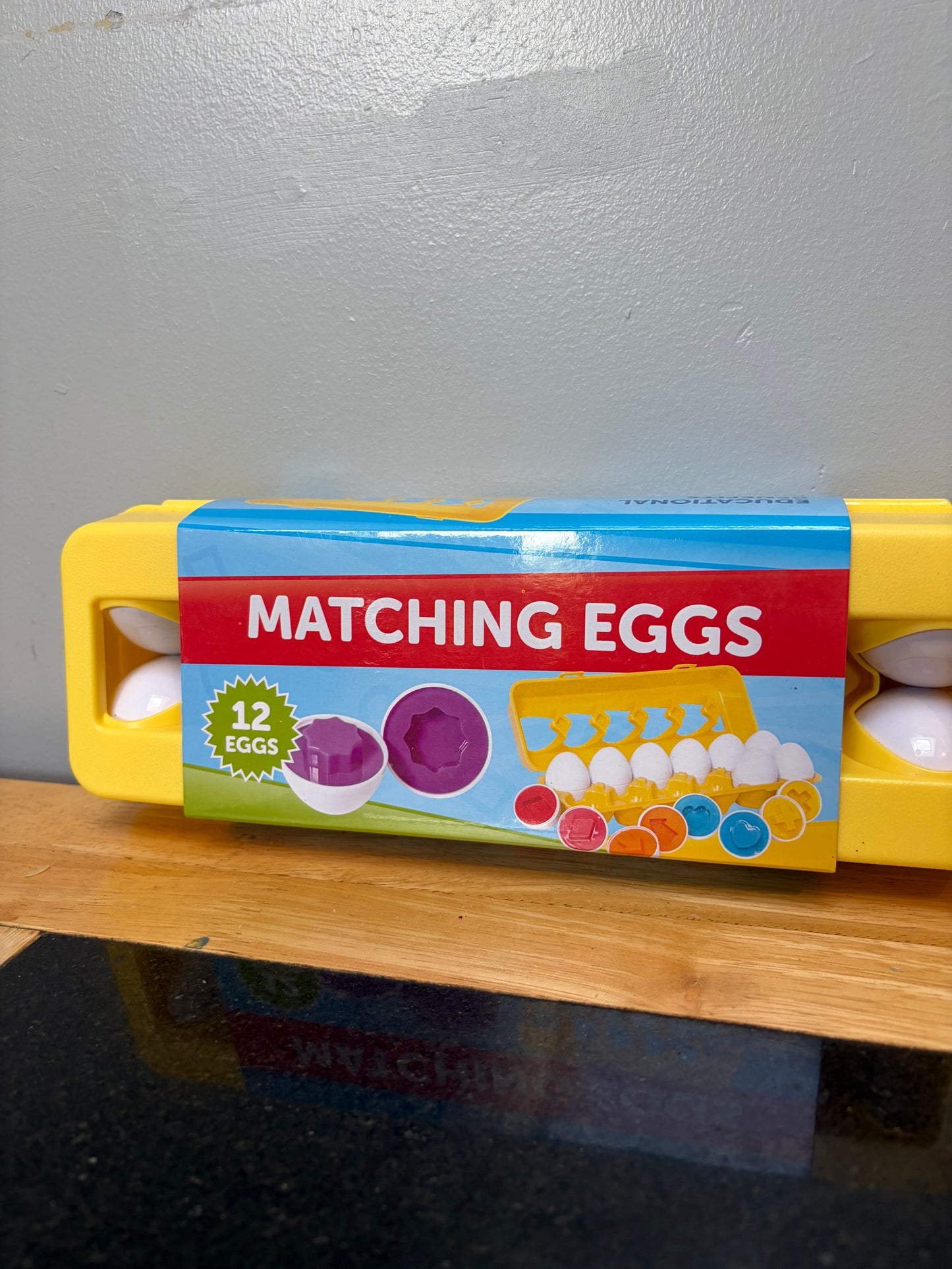 Set of 12 matching shape and color toy eggs in yellow carton, close up view