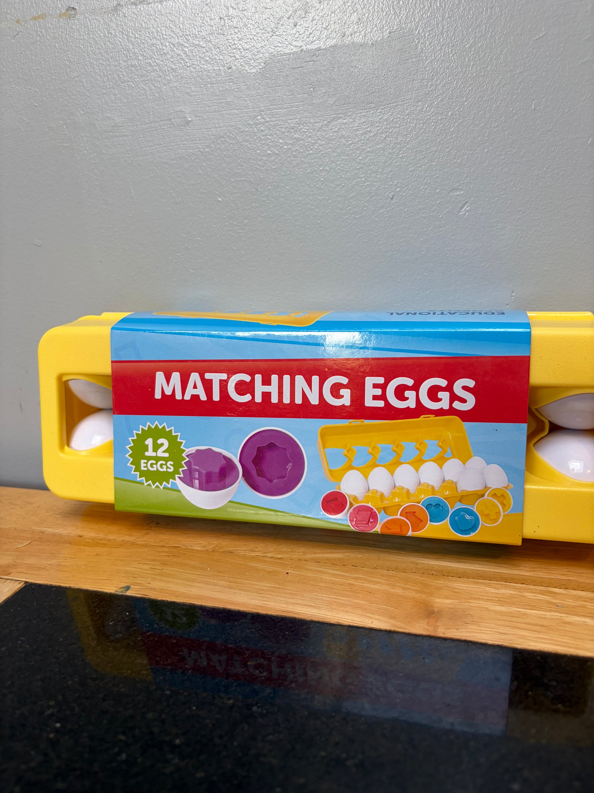 Set of 12 matching shape and color toy eggs in yellow carton, close up view