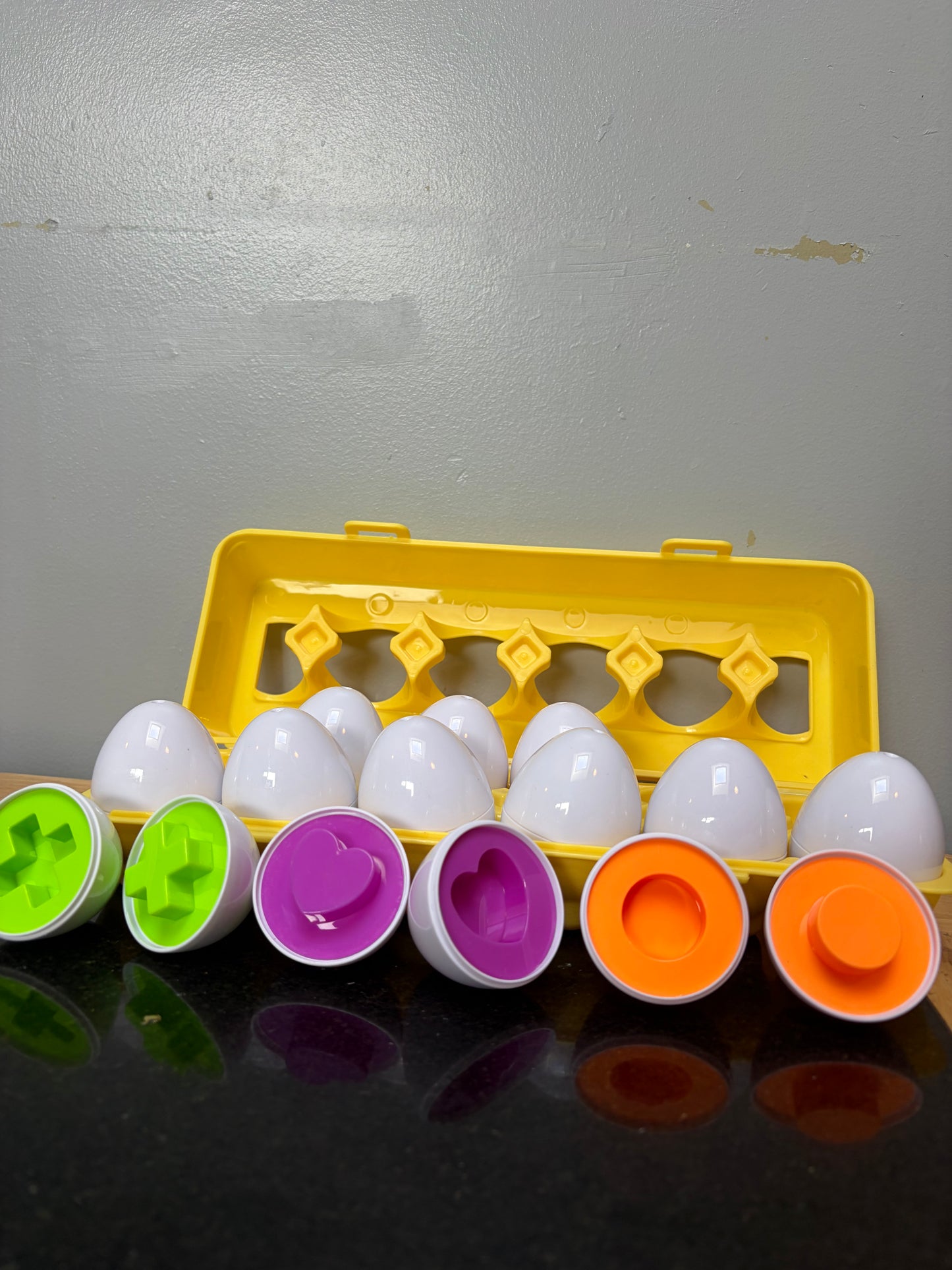 Set of 12 matching shape and color eggs in yellow carton opened showing the toy eggs